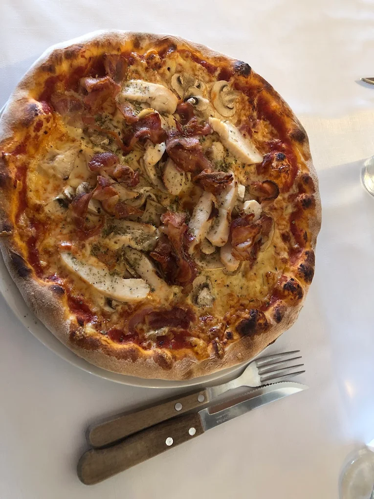 Sprød pizza med kylling, bacon og champignon serveret på hvid dug hos Ristorante Italia i Odder